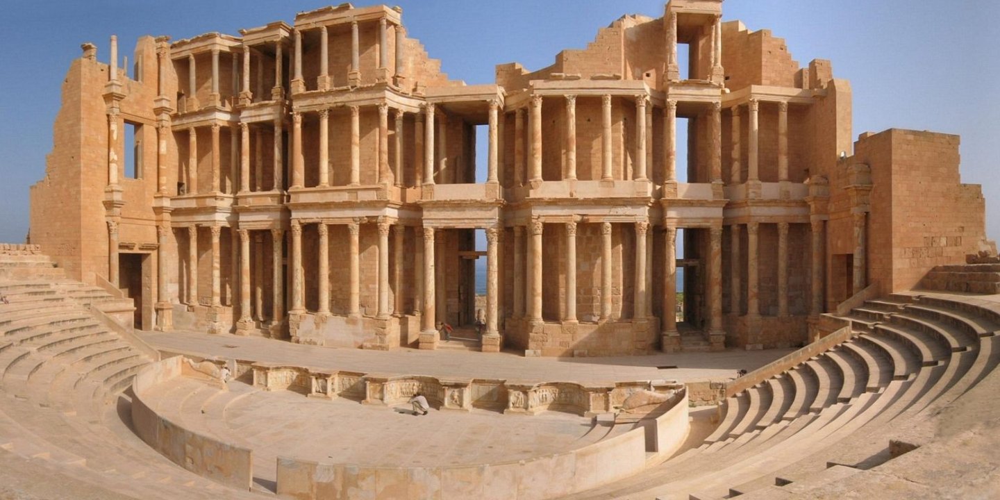 Sabratha lies to the North West of Libya on the coast with spectacular sea views. This city has been declared a UNESCO World Heritage Site with it's trade port dating back to 500BC. The city today is ruins, but there are temples, a magnificent third century theater, a forum and so much more to see, giving you a true idea of the size of this once very busy port town in North Africa. The city was rebuilt after an earthquake struck the area in the fourth century, but took a rapid decline in the fifth century thanks to the Vandal misrules of the area. Soak Up The History Walking around Sabratha, you are able to soak up the history and culture of this once thriving port town. Take a walk through the stunning theater, a large part of this structure still stands today with it's impressive columns and arches adorned in beautiful artwork. Stop in at the Forum surrounded by crumbling walls. Take note of the decorative and inscribed pillars, monuments and fabulous mosaics. See the mosaics of the House of Jason Magnus, this is one of the many monuments standing for you to explore when visiting this port town of Sabratha. There is a host of temples, many lie in ruins, but you are still able to make out the magnitude of these once magnificent structures from the Isis Temple and Serapis Temple to the Liber Pater Temple and Antonine Temple. The Baths sit on the cliff edge overlooking the ocean offering spectacular sea views. The sandstone blocks complete with the magnificent mosaics show the beauty that the people once absorbed while enjoying what the baths had to offer. Before you leave stop in at the Museum of Sabratha which opened in 1932. Walk through the choice of galleries brimming with historical artifacts including mosaics and statues.
